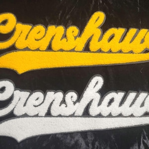 May include: Two embroidered patches with the word "Crenshaw" in a script font. One patch is yellow with a gray outline, and the other is white with a gray outline. The patches are on a black background.