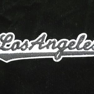 Pu&ograve; includere: Toppa ricamata in bianco e nero con la scritta "Los Angeles" in corsivo. La toppa ha un bordo bianco ed &egrave; posta su uno sfondo nero. Adatta per abbigliamento o accessori.