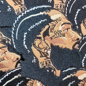 May include: Multiple black and brown embroidered patches with a profile of a person's face. The patches have white stitching around the edges and the text "PROLIPIC GOP WILLRISE" and "THE WOB" on them.