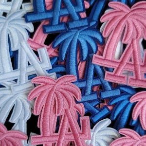 May include: Embroidered patches featuring the Los Angeles Dodgers logo and palm trees in blue, pink, and white. The patches are densely arranged, showcasing the team's iconic 'LA' emblem and tropical imagery.