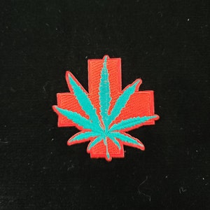 May include: A red medical cross with a teal green marijuana leaf inside. The patch is embroidered.