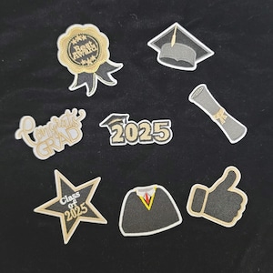 May include: A collection of graduation-themed patches in gold, black, and white. Designs include a graduation cap, diploma, star with "Class of 2025", "Best Award" ribbon, "Congrats Grad" text, the number "2025", a graduation gown, and a thumbs-up.
