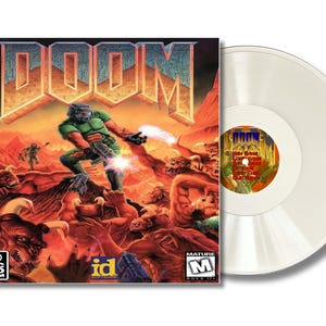 May include: A DOOM PC CD-ROM game cover featuring a green-armored character firing a weapon at various monsters in a rocky, orange-hued landscape, accompanied by a translucent white vinyl record with a central label displaying the game title.