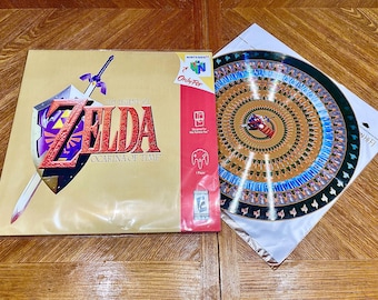 May include: The Legend of Zelda: Ocarina of Time video game for Nintendo 64. The game box features the game's title, a shield, and a sword. A decorative disc with a colorful design is also present.