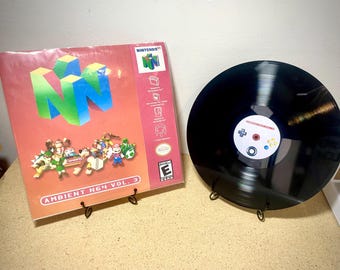May include: A vinyl record and album cover for Ambient N64 Vol. 3. The album cover features the Nintendo 64 logo in blue and green, with various game characters. The record has a controller design.