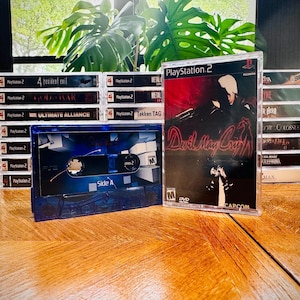 May include: A collection of PlayStation 2 video game cases and a blue cassette tape. The game cases include titles like "Devil May Cry" and "God of War." The cassette tape is labeled "Side A."