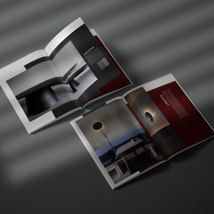 May include: Two open magazines displaying interior design photography. One spread shows a monochrome image of a table and the word "narrative". The other spread has a dark red background with the word "creativity".