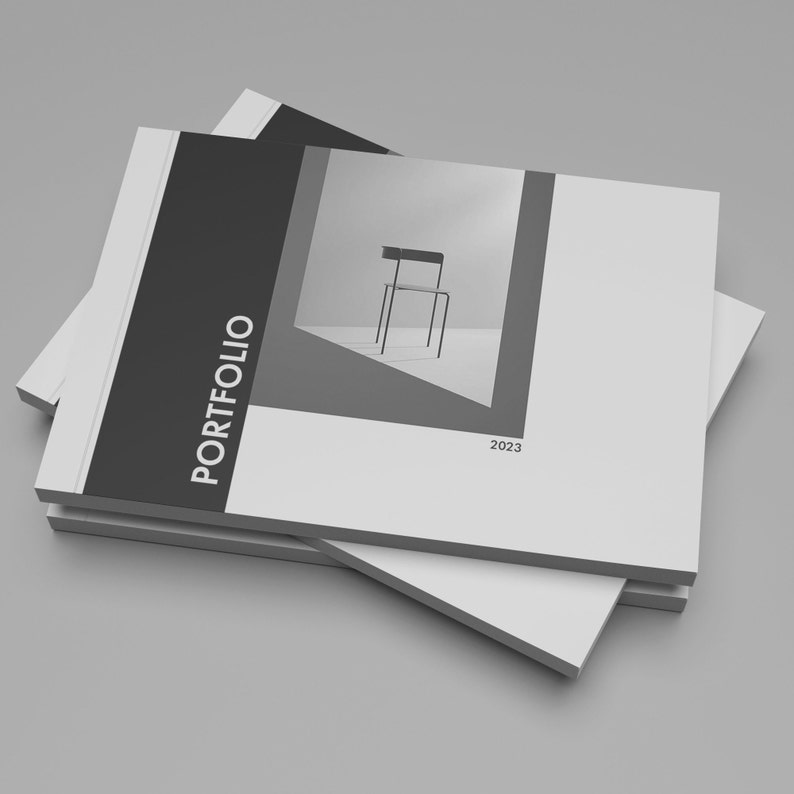 May include: A black and white portfolio with the word "PORTFOLIO" printed in white on the front cover. The year "2023" is printed in black at the bottom of the cover. The portfolio is closed and stacked on top of another portfolio.
