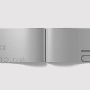 K&ouml;nnte beinhalten: Ein graues, geschlossenes Buch mit dem Text "xx house" auf der linken Seite und "01" auf der rechten Seite.