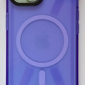 May include: A purple clear phone case with a built-in ring holder and a gold metal strap. The case has a textured design.