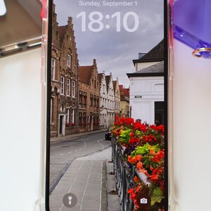 May include: A clear phone case with a raised bumper protects a smartphone displaying a photo of a street in a European city. The time on the phone screen is 18:10. The date is Sunday, September 1.