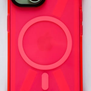 May include: A bright pink phone case with a clear back and a built-in magnetic ring holder. The case has a geometric pattern and a raised camera bump.