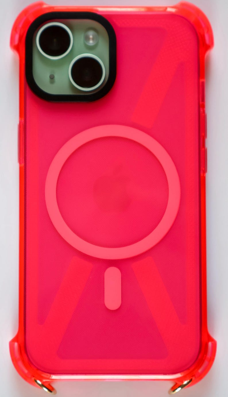 May include: A bright pink phone case with a clear back and a built-in magnetic ring holder. The case has a geometric pattern and a raised camera bump.