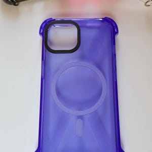 May include: A clear purple phone case with a ring holder and gold accents. The case has a textured design and is made of a durable material.