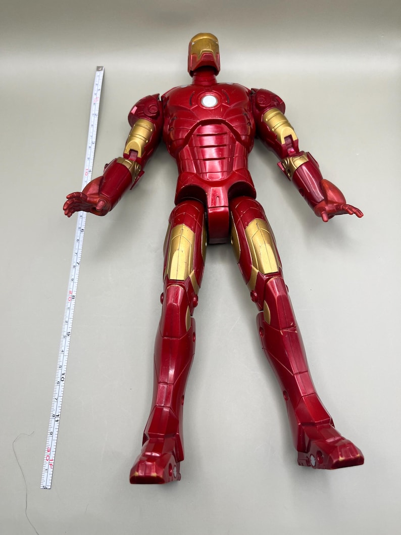 May include: A red and gold Iron Man action figure with articulated limbs. The figure is standing on a white surface.