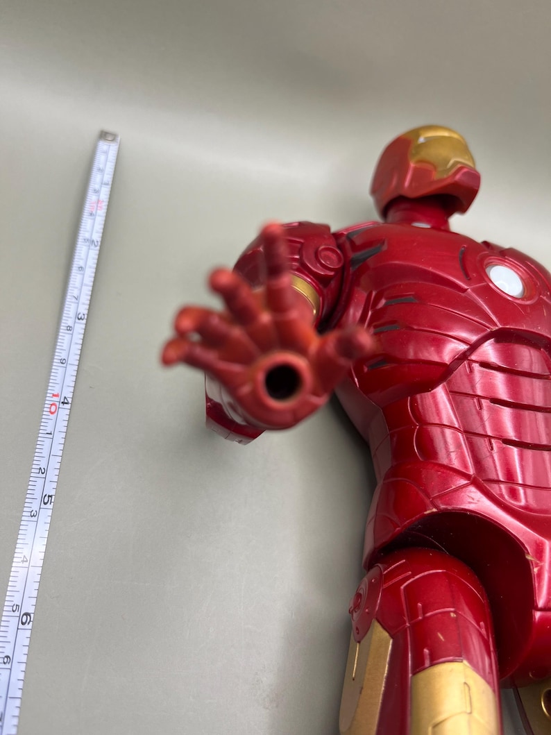 May include: Red and gold Iron Man action figure with articulated arms and legs. The figure is posed with its right hand outstretched.