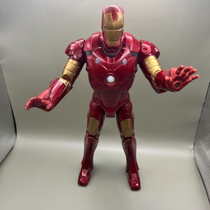 May include: Red and gold Iron Man action figure with a light-up chest. The figure is posed with arms outstretched, as if in a superhero stance.