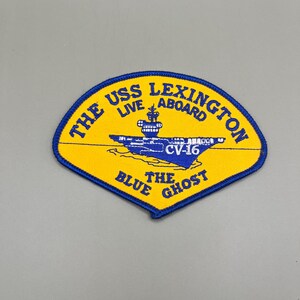 May include: A yellow and blue embroidered patch with the text "The USS Lexington Live Aboard CV-16 The Blue Ghost".