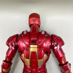 May include: Red and gold Iron Man action figure with a detailed design. The figure is posed with its back to the camera, showing off its intricate details.
