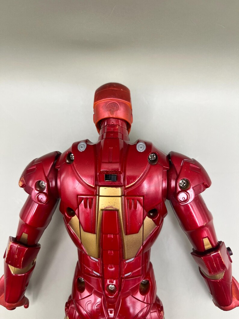 May include: Red and gold Iron Man action figure with a detailed design. The figure is posed with its back to the camera, showing off its intricate details.