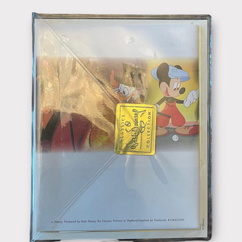May include: Sealed Disney Classics framed art print featuring Mickey Mouse playing golf. The artwork includes Donald Duck and a gold foil sticker that reads "Disney Classics Collection". The print is in a clear plastic case.