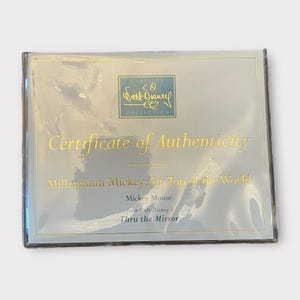 May include: A certificate of authenticity from the Walt Disney Classics Collection. The certificate is in a clear plastic sleeve. The text on the certificate reads "Certificate of Authenticity" and "Millennium Mickey: On Top of the World".
