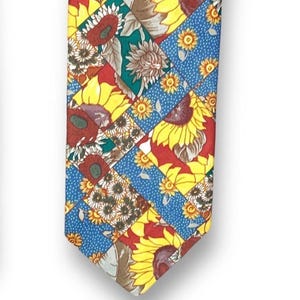 May include: A colorful necktie featuring a patchwork design with sunflowers. The tie has a variety of colors, including yellow, red, blue, and green. The sunflowers are in full bloom, with yellow petals and brown centers. The background is a mix of blue polka dots and red.