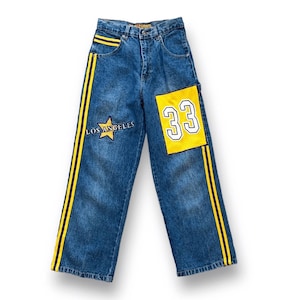 May include: Blue denim jeans with yellow and black stripes down the sides. The jeans feature a yellow patch with the number 33 and a star patch with "LOS ANGELES" on the left leg. The jeans have a classic five-pocket design.
