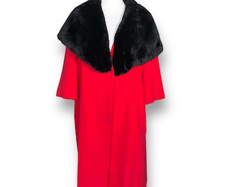 Puede incluir: Un abrigo rojo vintage con cuello de piel sintética negra. El abrigo tiene mangas cortas y un dobladillo hasta la rodilla. El abrigo se exhibe en un maniquí blanco.