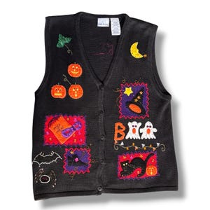 May include: A black knit button-front vest featuring embroidered Halloween motifs including orange pumpkins, a yellow crescent moon, a witch hat, white ghosts, a black cat, a spider, a bat, and an orange trick-or-treat bag with a purple mask.