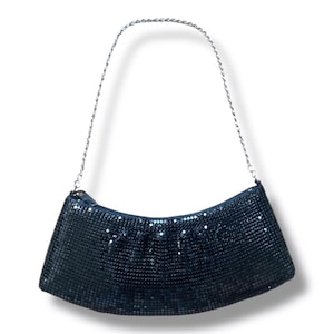 May include: A navy blue, mesh-style handbag with a silver chain strap. The bag has a curved shape and a zipper closure. The mesh material gives the bag a shimmering appearance.