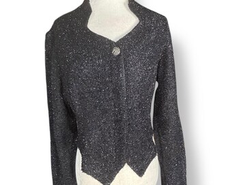 May include: A black, textured jacket with a single button closure. The jacket has a unique collar and a decorative hemline. The fabric has a subtle sparkle, adding a touch of elegance. The jacket is displayed on a mannequin.