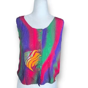 May include: A sleeveless top with a vibrant, colorful design. The top features a mix of pink, green, purple, and blue vertical stripes. It has a scoop neckline, wooden buttons, and a pocket with an abstract design in orange and yellow.