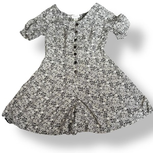May include: A vintage floral print dress with short sleeves and a button-down front. The dress features a black background with a white and gray floral pattern. The dress has a scoop neckline and a flared skirt.