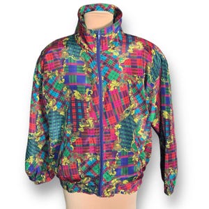 May include: A vintage, colorful jacket with a high collar and a full-length blue zipper. The jacket features a vibrant plaid pattern in red, green, blue, and yellow, with gold floral accents. The jacket has elastic cuffs and hem.