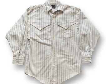 May include: A long-sleeved, button-down shirt with a cream-colored base and vertical black pinstripes. The shirt features two chest pockets with pointed flaps and buttoned cuffs. The collar is a classic spread style.