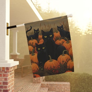 Może przedstawiać: Flaga ogrodowa na Halloween z motywem czarnego kota. Flaga przedstawia cztery czarne koty siedzące wśród stosu pomarańczowych dyni. Tło jest w stonowanym brązowym kolorze.