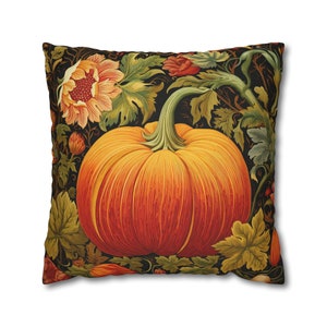 May include: A decorative throw pillow with a large orange pumpkin surrounded by green leaves and flowers on a black background.