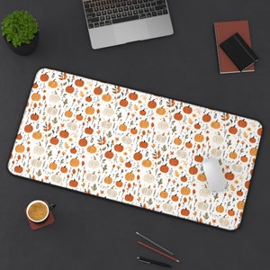 May include: A white mouse pad with a repeating pattern of orange pumpkins and green leaves on a white background.