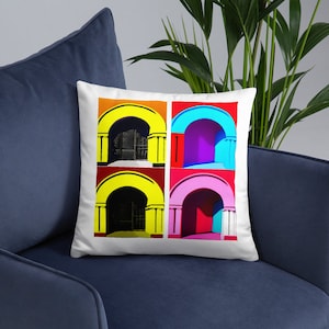 Può includere: Un cuscino bianco con un design pop art colorato che presenta quattro archi con porte. Gli archi sono di colore giallo, rosso, rosa e blu con porte nere.