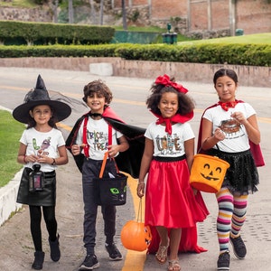 May include: Four children dressed in Halloween costumes trick-or-treating. The child on the left is wearing a witch costume with a black hat and a black dress. The child in the middle is wearing a vampire costume with a red cape and a white shirt that says "Trick or Treat". The child on the right is wearing a red dress and a white shirt that says "I Love Halloween". The child on the far right is wearing a white shirt with a pumpkin on it and a red cape.