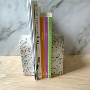 This arch bookend is perfect for adding style to any mantel, dresser, or desk or for using as book ends. The images show the white terrazzo style, which also comes in navy, hunter green, or beige. Each terrazzo piece is unique. Made of gypsum cement