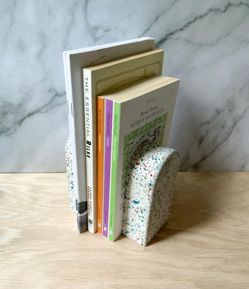 This arch bookend is perfect for adding style to any mantel, dresser, or desk or for using as book ends. The images show the white terrazzo style, which also comes in navy, hunter green, or beige. Each terrazzo piece is unique. Made of gypsum cement