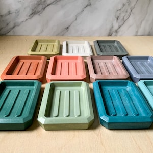 May include: A set of ten rectangular soap dishes in various colors, including green, blue, pink, and orange. The dishes have a textured surface and are made of a durable material.