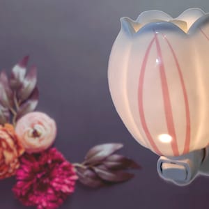 May include: White ceramic plug-in wax warmer shaped like a tulip with pink stripes. The warmer has a light inside and a switch on the side.