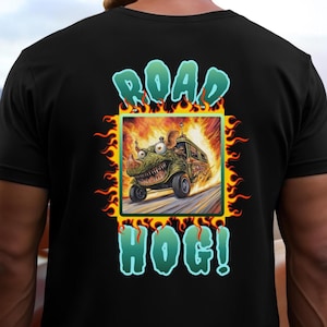 May include: Black t-shirt featuring a cartoon illustration of a green monster driving a vehicle engulfed in flames. The text "ROAD HOG!" is displayed above and below the image in a stylized font.