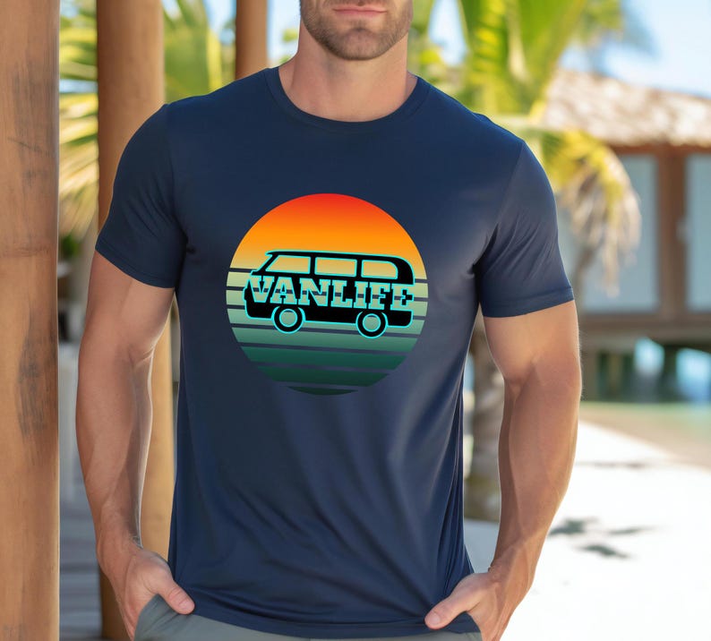 Peut inclure: T-shirt bleu marine avec un motif circulaire repr&eacute;sentant un van et le texte "VANLIFE". Le motif pr&eacute;sente un coucher de soleil avec des teintes orange, jaune et verte. Le t-shirt est de style col rond.