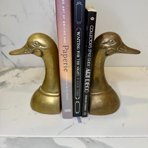Pair of large vintage solid brass duck head bookends. Although a matching pair slightly different hue of brass between bookends. Gorgeous!