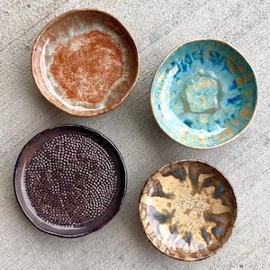 May include: A white ceramic mug with a black handle and the text "But First, Coffee" in a black, bold font. The mug is sitting on a wooden surface.