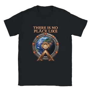 May include: A black short-sleeve t-shirt featuring a graphic of a circular metallic gate framing a view of Earth. Above the gate, the text reads THERE IS NO PLACE LIKE in a metallic font. The design includes orange glowing accents on the gate.